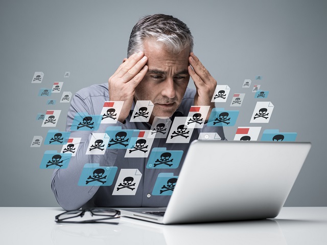 Businessman working with a computer full of viruses. He is frustrated with head in hands. Malware concept Intersys Ltd