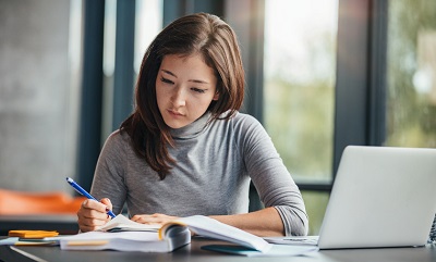 Shot of young woman taking down notes in diary, as part of training to increase her employer's Microsoft partner list of competencies.