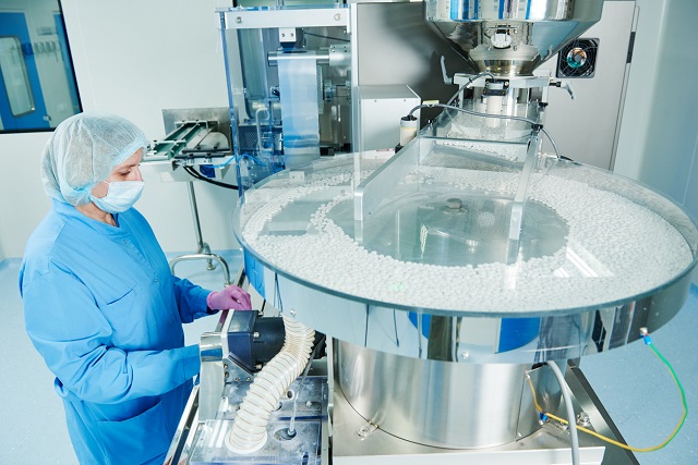EU FMD Compliance - Pharmaceutics. Pharmaceutical worker operates tablet blister packaging machine