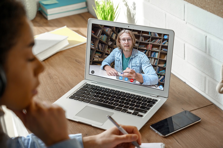 close up of laptop with video conference with bearded man in glasses holding a pen